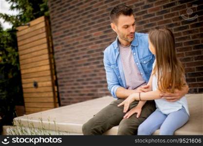 Father and his cute daughter have a good time in front of the house door