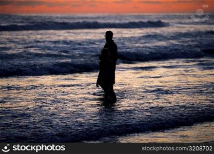 Father and his daughter standing in the water at the beach