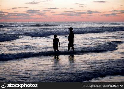 Father and his daughter standing in the water at the beach