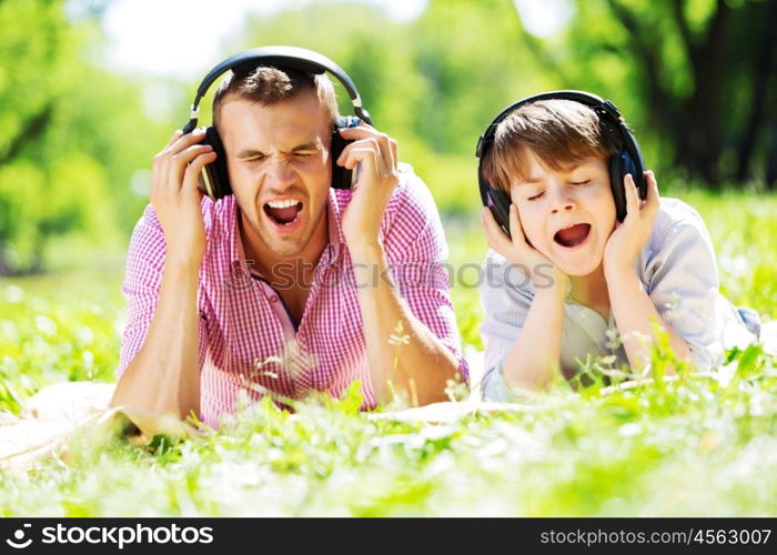 Father and kid in summer park enjoying music. Weekend in park