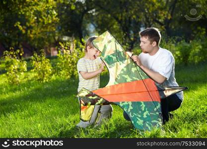 Father and small son are going to fly flying kite in park