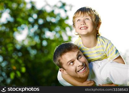 Father and small son frolic in a summer garden