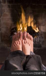 Father and son&acute;s feet warming at a fireplace