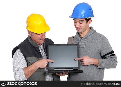 Father and son builder team pointing at laptop