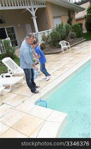 Father and son cleaning swimming-pool
