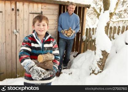 Father And Son Collecting Logs From Wooden Store In Snow