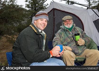 Father and son drinking by tent