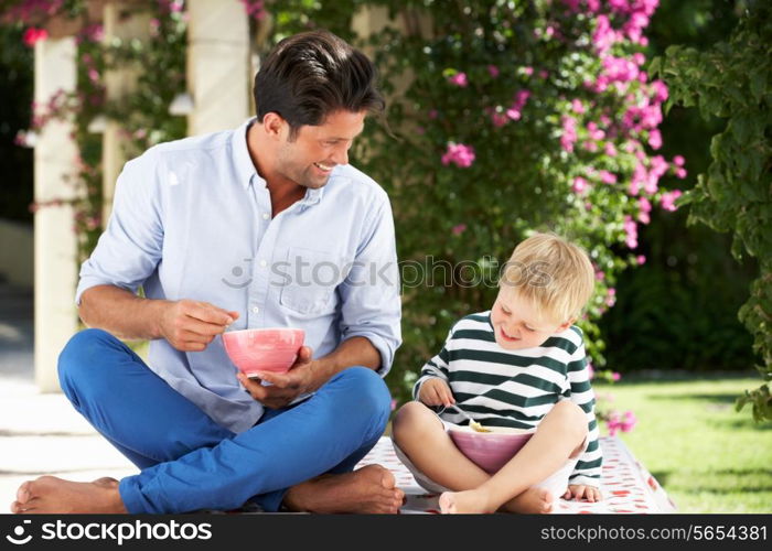 Father And Son Enjoying Breakfast Cereal Outdoors Together