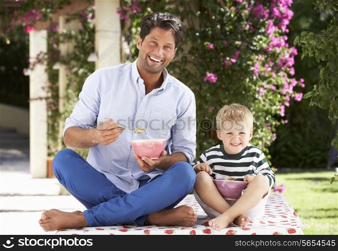 Father And Son Enjoying Breakfast Cereal Outdoors Together