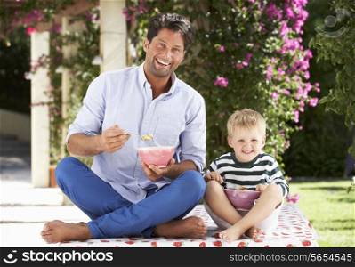 Father And Son Enjoying Breakfast Cereal Outdoors Together