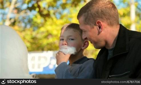 father and son enjoying cotton candy at a fair