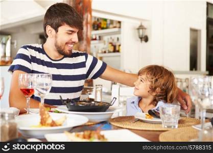 Father And Son Enjoying Meal In Restaurant