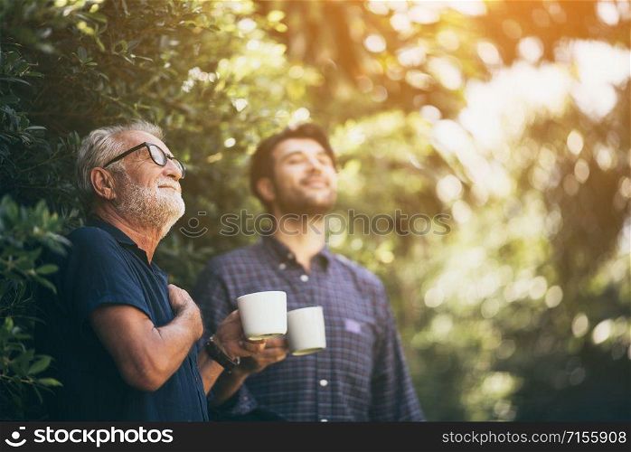 Father and son enjoying the morning coffee. In the backyard
