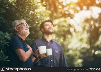 Father and son enjoying the morning coffee. In the backyard