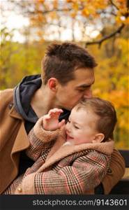 Father and son have fun together in park in autumn. Outdoor fun, autumn fallen leaves. Dad loves his boy. Father and son have fun together in park in autumn. Outdoor fun, autumn fallen leaves. Dad loves his boy.