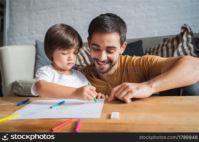 Father and son having fun while drawing together at home. Monoparental family concept.