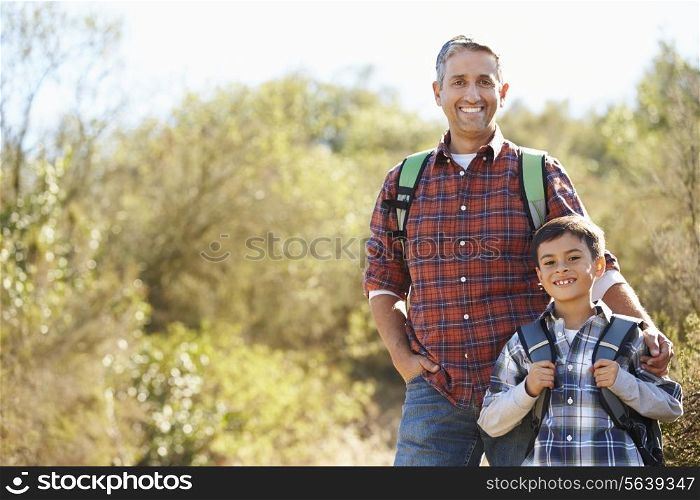 Father And Son Hiking In Countryside Wearing Backpacks
