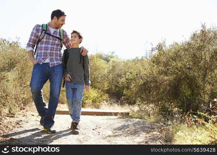 Father And Son Hiking In Countryside Wearing Backpacks