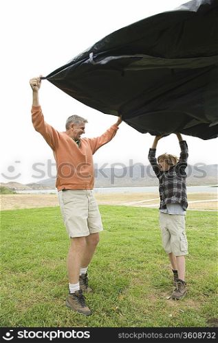 Father and son hold groundsheet in wind