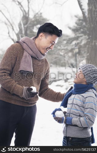 Father and son holding snowballs