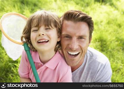 Father And Son In Field With Insect Net