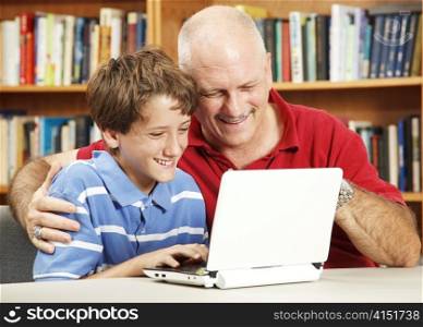 Father and son in the library using a small netbook computer.