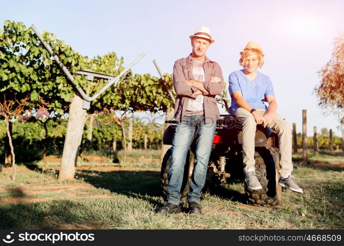 Father and son in vineyard. Father and son standing next to car in vineyard