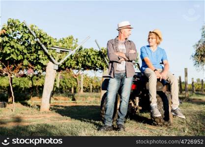 Father and son in vineyard. Father and son standing next to car in vineyard