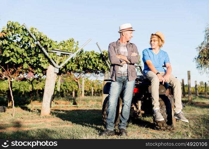 Father and son in vineyard. Father and son standing next to car in vineyard