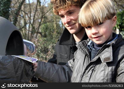 Father and son inserting leaflets into a bin