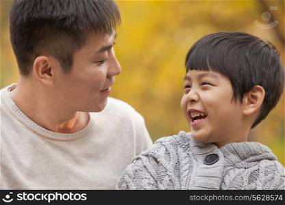 Father and son laughing in the park in autumn, close-up