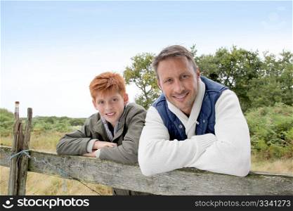 Father and son leaning on a fence