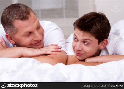 Father and son looking into each others eyes and relaxing in bed
