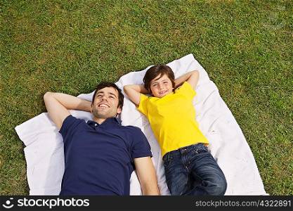 Father and son lying on blanket, high angle
