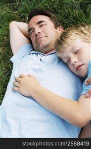 Father and son lying outdoors sleeping