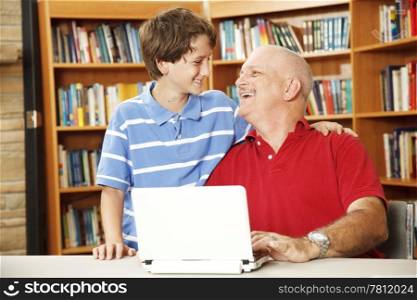 Father and son or teacher and student have fun using the computer in the school library.