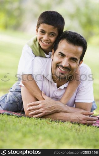 Father and son outdoors in park embracing and smiling (selective focus)