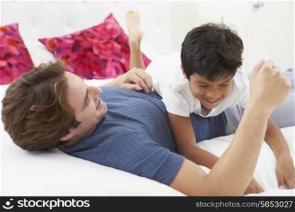 Father And Son Playing In Bed Together