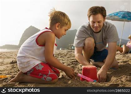 Father and Son Playing in Sand at Beach