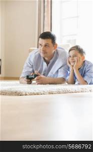 Father and son playing video game on floor at home