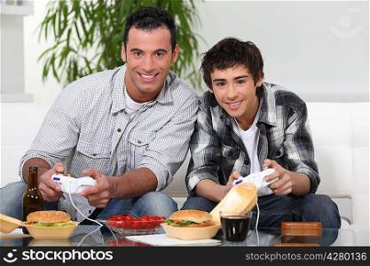 Father and son playing video games and eating junk-food