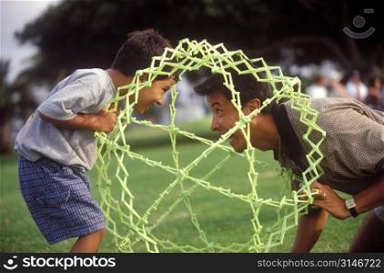 Father And Son Playing With A Hoberman Sphere In The Park