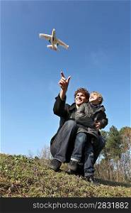 Father and son playing with toy plane in field