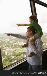 Father and son pointing from observation deck at Tower of the Americas in San Antonio, Texas.