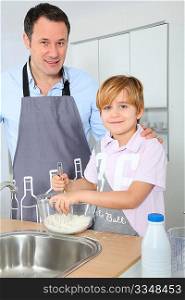 Father and son preparing cake in kitchen