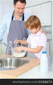 Father and son preparing cake in kitchen
