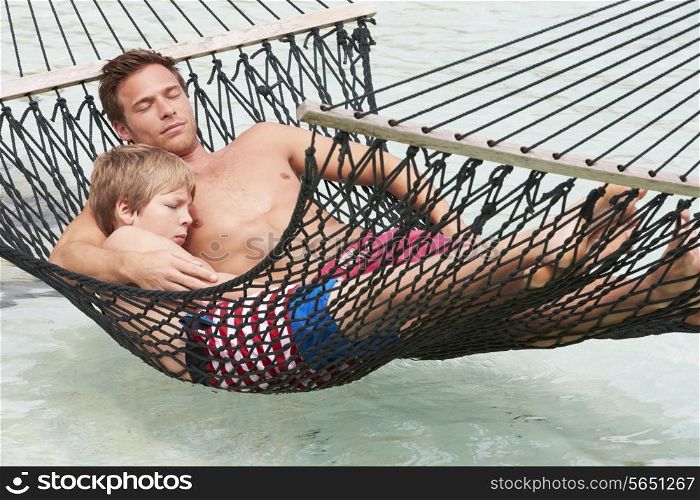Father And Son Relaxing In Beach Hammock