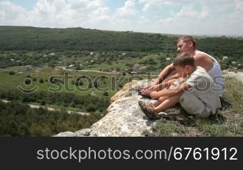 Father and son resting after climbing up mountain