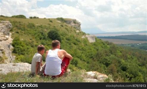 Father and son resting after climbing up mountain