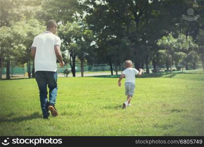 Father and son running and chasing each other in green park